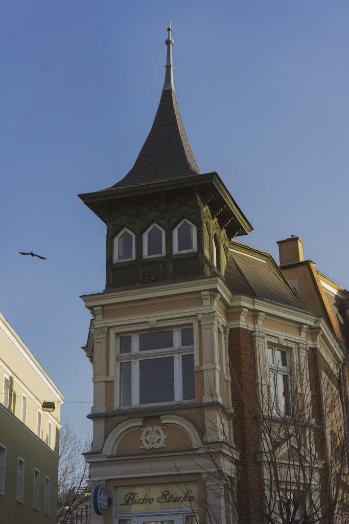 A charming historic building in Opole, Poland, with a bird flying above under a clear blue sky.